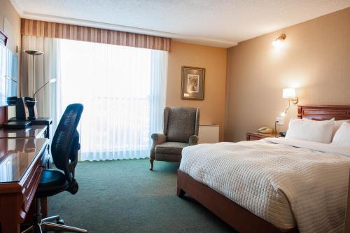 a hotel room with a bed and a chair and a window at Hôtel Castel in Granby