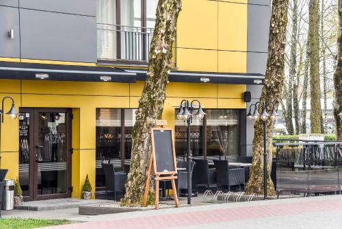 a yellow building with trees in front of it at Muza Hotel in Palanga