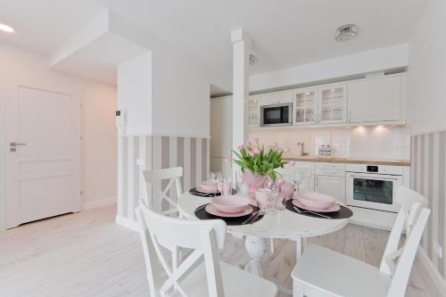 a white kitchen with a white table and chairs at Apartamenty Gdańsk EU - Waterlane in Gdańsk