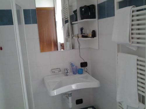 a white bathroom with a sink and a mirror at Hotel Rezia in Sondalo