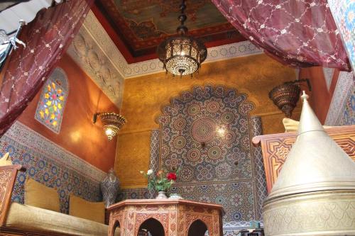 Habitación con una gran pared ornamental y una lámpara de araña. en Riad Bibtia, en Marrakech