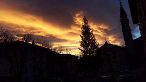 a sunset with a clock tower and a church at Albergo Casavecchia in Tiarno di Sopra