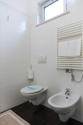 a white bathroom with a toilet and a sink at Hotel Miramare in Pineto