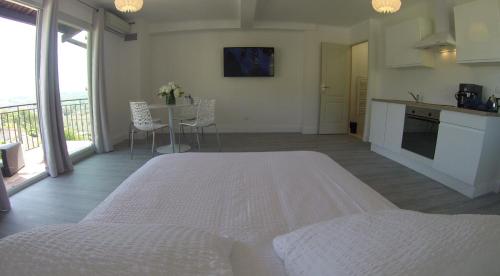 a white bedroom with a white bed and a kitchen at Maison Carles BnB in La Colle-sur-Loup