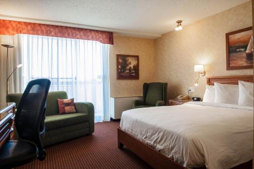 a hotel room with a bed and chairs and a window at Hôtel Castel in Granby