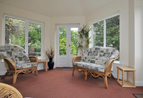a living room with two chairs and windows at Marton Grange Country House in Bridlington