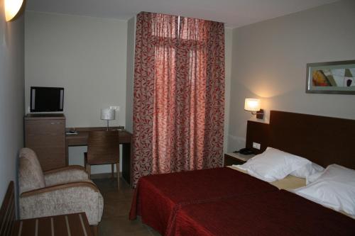 a hotel room with a bed and a chair and a desk at Hotel Ciutat de Carlet in Carlet