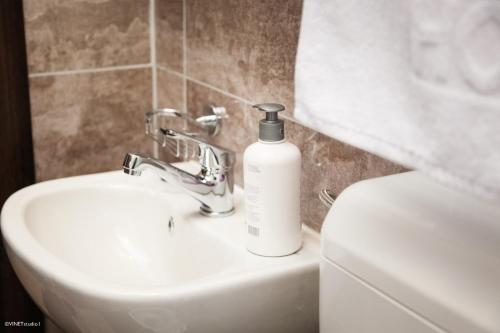 a white bottle of soap is sitting on a bathroom sink at Becar Pyramid Rooms in Visoko