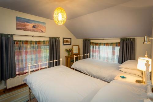 a bedroom with two beds and a chandelier at 1 Tan Yr Eglwys Barn Cottage in Pontardawe