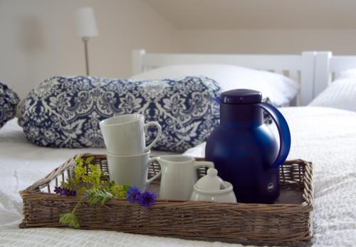 una cesta con tazas y un jarrón azul en una cama en SEASIDE APARTMENTS - SUNNY BLUE, en Eckernförde