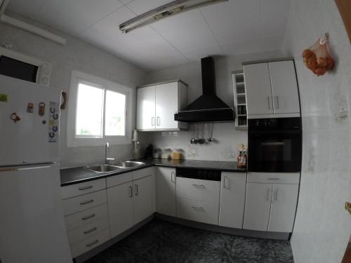 uma cozinha com armários brancos, um lavatório e um frigorífico em LG Big Flat Barcelona em Badalona