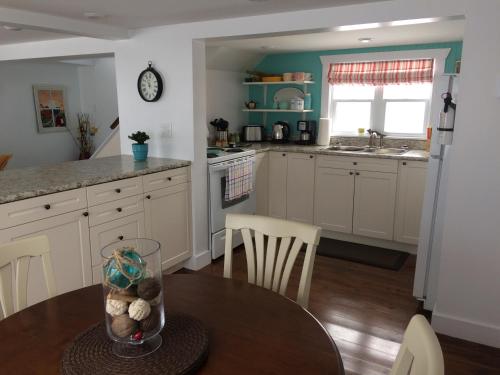 a kitchen with white cabinets and a table with chairs at Seakissed Cottage in Bonavista