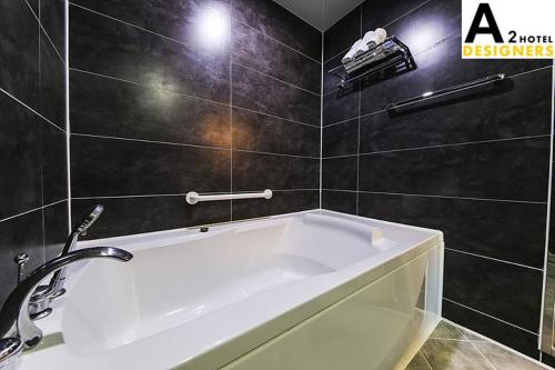 a bath tub in a bathroom with black tiles at A2 Hotel Desingers in Yesan