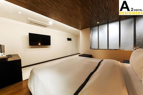 a bedroom with a large white bed and a flat screen tv at A2 Hotel Desingers in Yesan