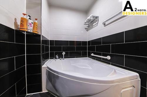 a bathroom with a white tub and a black tiled wall at A2 Hotel Desingers in Yesan