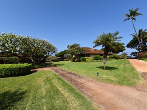 a house with a palm tree and a dirt road at Kaanapali Plantation #52 Condo in Lahaina
