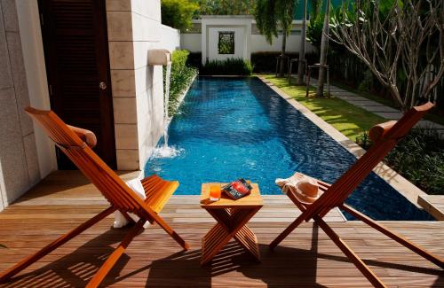 two chairs and a table next to a swimming pool at Two Villas HOLIDAY - Oxygen Style Bangtao Beach, Phuket in Bang Tao Beach