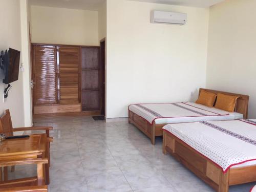 a bedroom with two beds and a table and a window at Bắc Nam Hotel in Da Nang