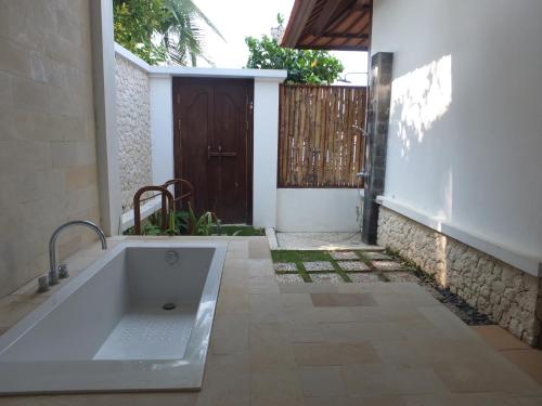 a bathroom with a bath tub in front of a door at The Amrita - Salt Farm Villas in Tejakula