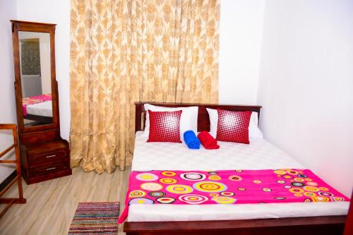 a bedroom with a bed with red and yellow pillows at Marcelin Family Villa in Negombo