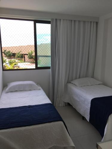 2 camas en una habitación con ventana en Nui Supreme Beach Living, en Porto de Galinhas