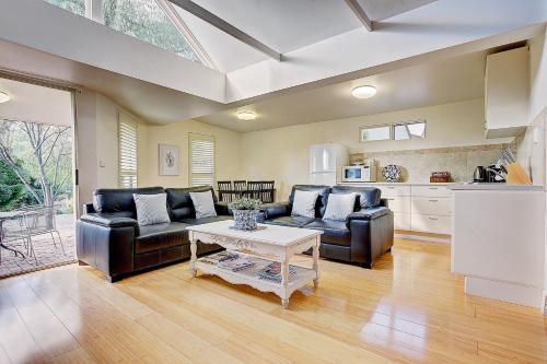 a living room with two leather couches and a table at Evanslea Luxury Boutique Accommodation in Mudgee