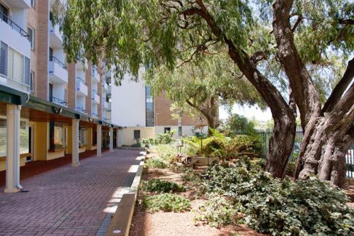 an empty sidewalk in front of a building with trees at Ocean Harbour Views in Fremantle