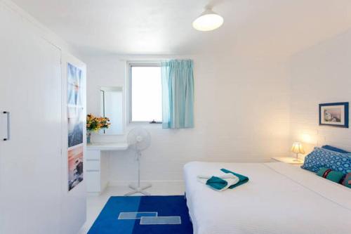 - une chambre avec un lit blanc et un tapis bleu dans l'établissement Ocean Harbour Views, à Fremantle