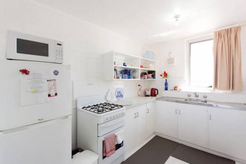 a white kitchen with a stove and a microwave at Ocean Harbour Views in Fremantle