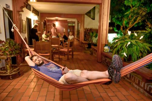 a man laying in a hammock in a living room at Macondo Hostel in San Gil