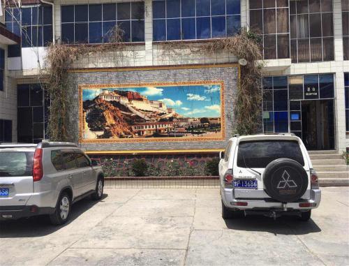 two cars parked in a parking lot in front of a building at Overseas Tibetan Hotel in Xiahe