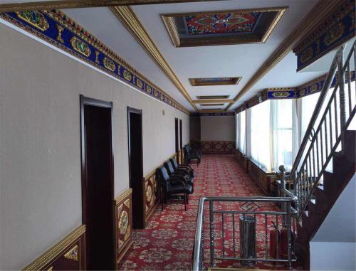 a hallway with stairs and chairs in a building at Overseas Tibetan Hotel in Xiahe