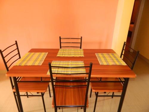 mesa de comedor con sillas y mesa de madera con servilletas amarillas en Eastin Homestay, en Guwahati