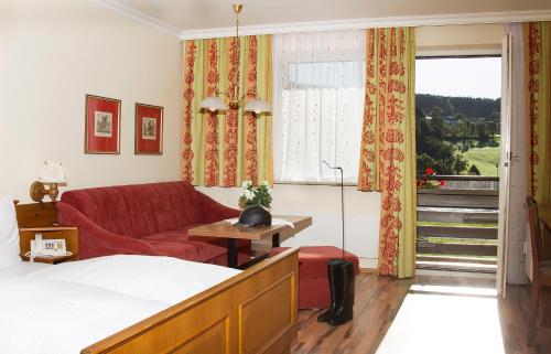 Habitación de hotel con sofá rojo y ventana en Hotel Reitzentrum Hausruckhof, en Ampflwang im Hausruckwald