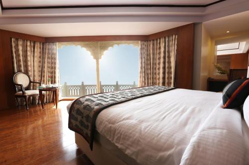 - une chambre avec un grand lit et une grande fenêtre dans l'établissement Golden Tulip Jaipur, à Jaipur