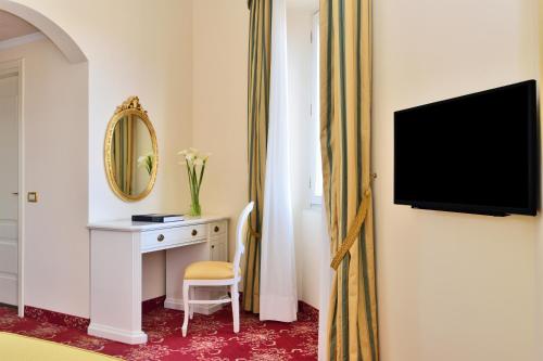 a hotel room with a desk and a television at Grand Hotel Cadenabbia in Griante Cadenabbia