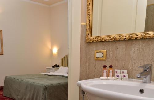 a bathroom with a sink and a mirror and a bed at Grand Hotel Cadenabbia in Griante Cadenabbia