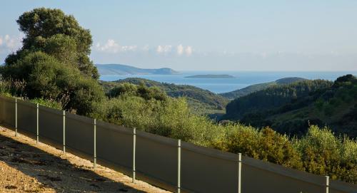 a fence on a hill with a view of the ocean at Afentiko Pigadi in Methoni