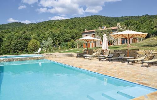uma piscina com cadeiras e guarda-sóis e uma casa em Casa Uliveto in Molino Vitelli em Casella