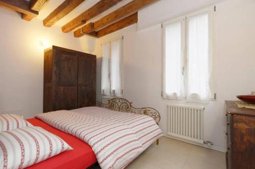 a bedroom with a red bed and two windows at Salizada San Francesco in Venice
