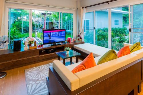 ein Wohnzimmer mit einem Sofa und einem TV in der Unterkunft Irawan House in Ao Nang Beach