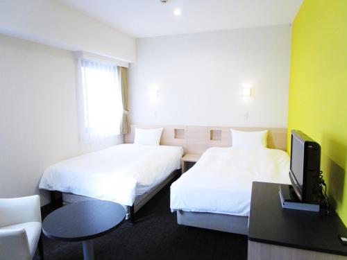 een hotelkamer met 2 bedden en een televisie bij Smile Hotel Utsunomiya Higashiguchi in Utsunomiya