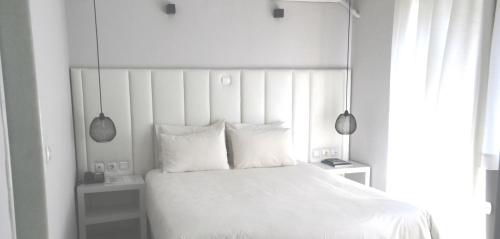a bed with white sheets and pillows in a bedroom at Capsis Hotel Thessaloniki in Thessaloniki