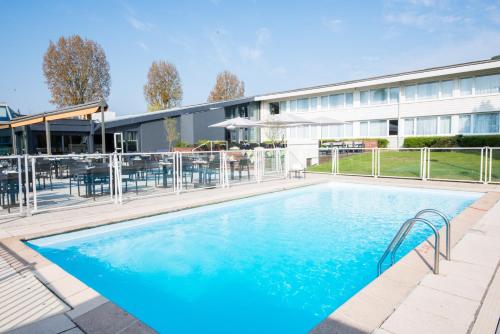 a swimming pool with a pool table and chairs at Novotel Lille Aéroport in Lesquin