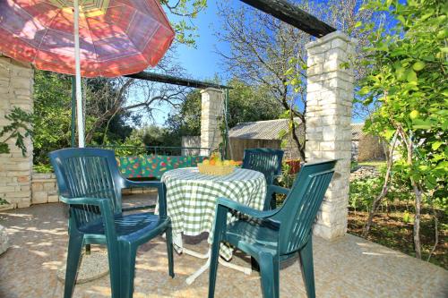 a table and chairs with a table and an umbrella at Stone House Oreb`s Cottage in Vela Luka