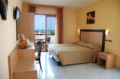 a hotel room with a bed and a table and a balcony at Marc Hotel in Vieste