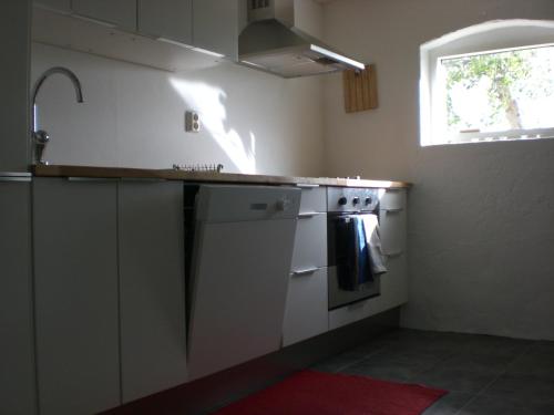 a kitchen with a sink and a stove and a window at Ola-Nils Gård in Borrby