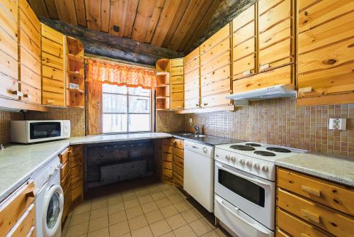 cocina con armarios de madera y horno de fogón blanco en Pikku-Junga, en Kuusamo