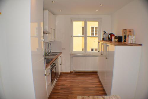 una cucina con pareti bianche, pavimenti in legno e una finestra di Apartment Avenzio a Würzburg
