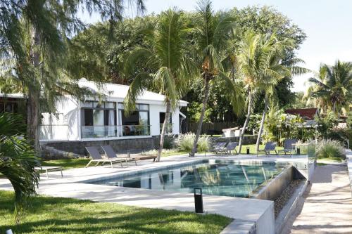 a swimming pool in front of a house with palm trees at Les 2 canons in Flic-en-Flac